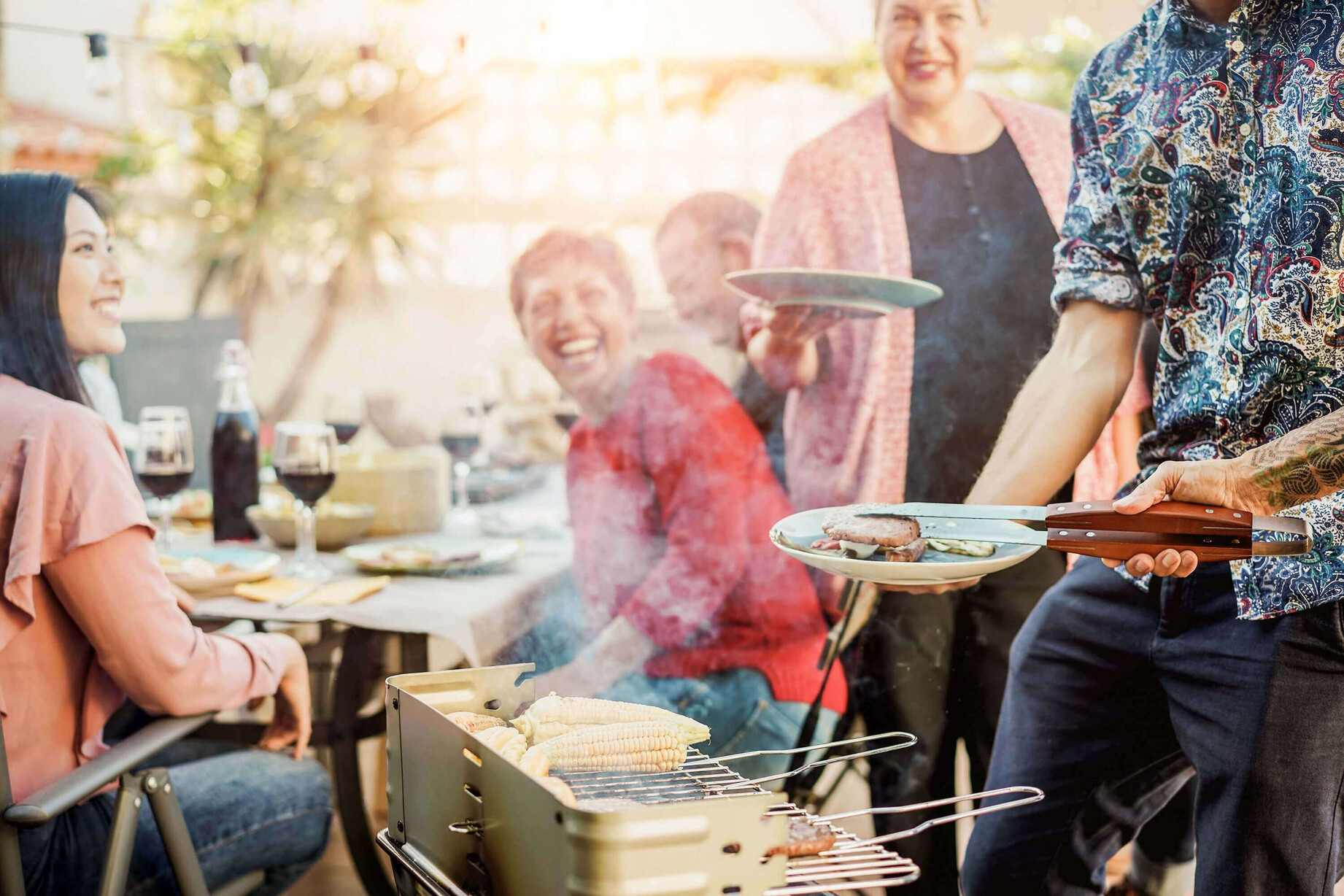 röhliche Grillrunde mit Wein und Speisen, Menschen genießen die gesellige Stimmung.